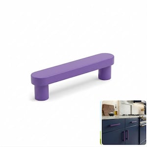 May include: A solid purple cabinet pull with a smooth, matte finish and a rounded, elongated rectangular bar design supported by two cylindrical posts. The hardware features a clean, uniform color and a simple, functional shape for cabinetry.