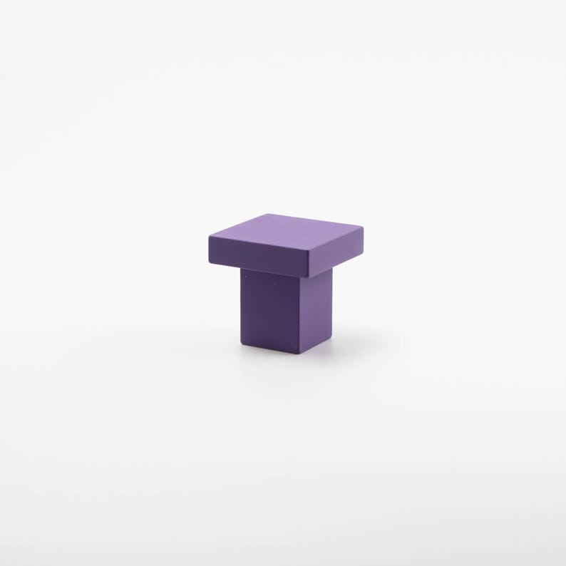 K&ouml;nnte beinhalten: Ein quadratischer Schrank-Knopf in Lila mit quadratischer Basis.