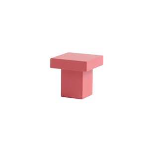 K&ouml;nnte beinhalten: Ein quadratischer rosa Schrank-Knopf mit quadratischer Basis.