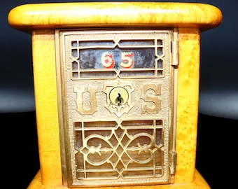 May include: A vintage wooden mailbox with a brass door and a glass window. The door has a Yale lock and the number "65" is visible in the window. The mailbox is labeled "U.S. Mail".