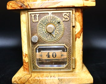 May include: A vintage wooden US mailbox with a brass door and a circular dial with letters. The mailbox has a glass window with the number 40 inside.