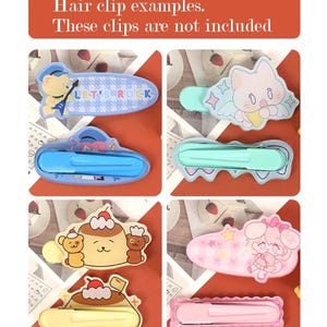 May include: A collection of colorful hair clips with various cartoon designs, including a bear, cat, and pudding characters. The clips are in shades of blue, green, yellow, and pink. Text at the top reads "Hair clip examples. These clips are not included."