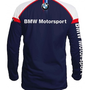 May include: A navy blue long-sleeve shirt with white and red accents. The shirt features the BMW Motorsport logo on the back and the BMW logo on the left sleeve. The right sleeve has the text "BMW Motorsport" printed vertically.