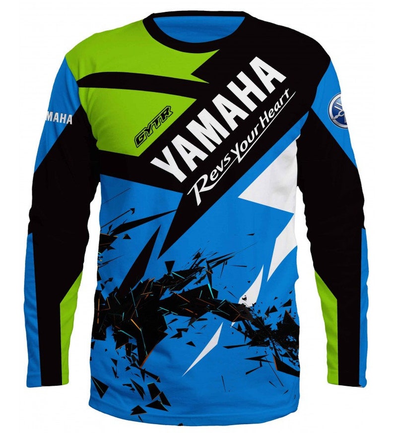 Puede incluir: Una camiseta de manga larga azul, negra, verde y blanca con un dise&ntilde;o gr&aacute;fico que presenta el logotipo de Yamaha y el texto "Yamaha Revs Your Heart".