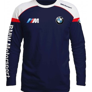 May include: A navy blue long-sleeved shirt with white and red accents. The shirt features the BMW Motorsport logo on the right shoulder and the BMW M logo on the left chest. The words "BMW Motorsport" are printed on the right sleeve.