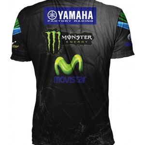 Puede incluir: Camiseta negra con un logotipo de Monster Energy verde y amarillo, un logotipo de Yamaha Factory Racing azul y un logotipo de Movistar verde y amarillo.