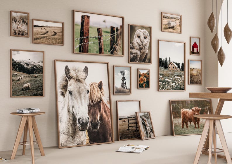 May include: A gallery wall featuring a variety of framed prints with rustic and farmhouse themes. The prints include images of horses, owls, barns, and landscapes. The prints are arranged in a symmetrical pattern on a light beige wall.