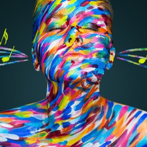 May include: A person with their eyes closed, covered in colorful paint, with musical notes flowing out of their ears.