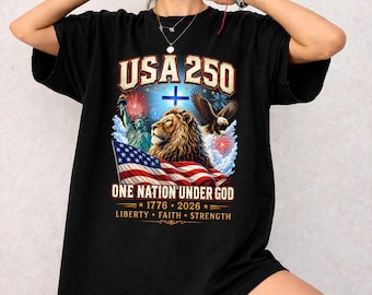 May include: Black t-shirt with a patriotic design. The graphic includes the text "USA 250" above an image of a lion, an eagle, and the American flag. The phrase "One Nation Under God" is also featured.