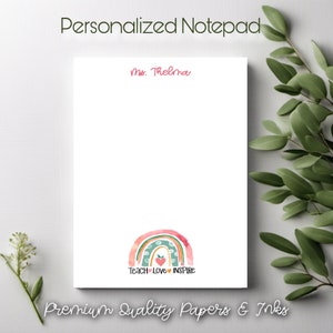 May include: Personalized notepad with a pink and green rainbow design and the text "Teach Love Inspire". The notepad has a white background and the name "Ms. Thelma" is written at the top.