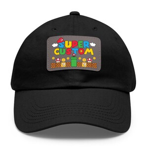 May include: Black baseball cap with a gray patch featuring a Super Mario Bros. themed design. The patch says "SUPER CUSTOM" with a star and a pipe.