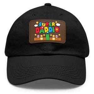 May include: Black baseball cap with a brown patch featuring a Super Mario Bros. themed design. The patch says "SUPER DADDIO" with a star, a mushroom, and a pipe.