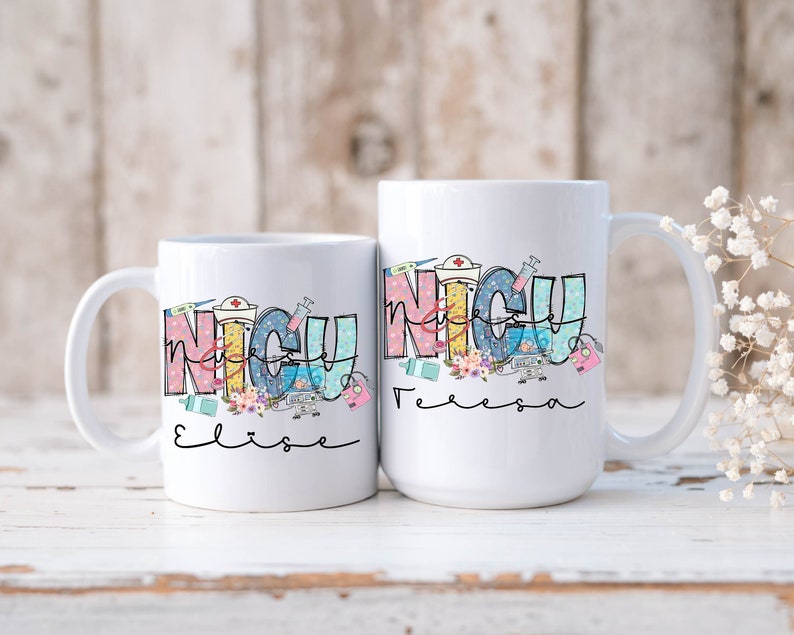 Puede incluir: Dos tazas de cer&aacute;mica blanca con un gr&aacute;fico colorido de la palabra "NICU" con s&iacute;mbolos m&eacute;dicos y los nombres "Elise" y "Felicia" escritos debajo.