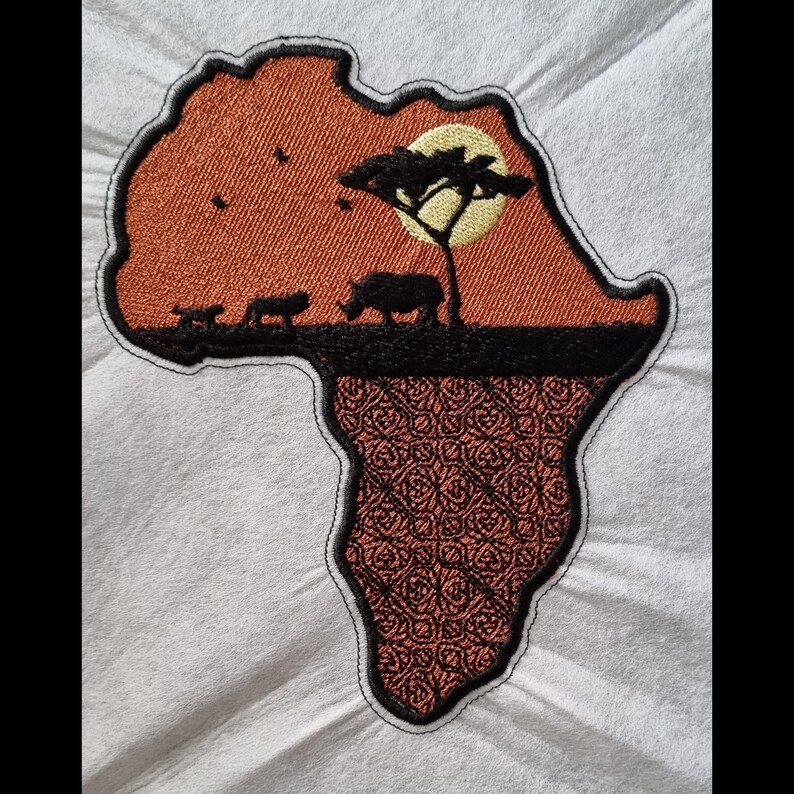 May include: An embroidered patch shaped like the continent of Africa. The patch is orange with a black outline and features a silhouette of a rhino, two lions, a tree, and a yellow sun. The bottom of the patch is a brown and black patterned design.