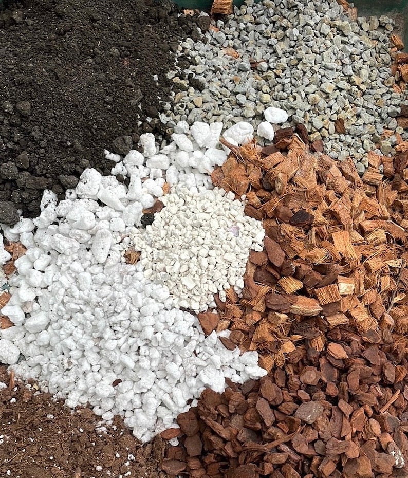 May include: A close-up of four different types of soil: black potting soil, white gravel, white coco chips, and brown coco chips.