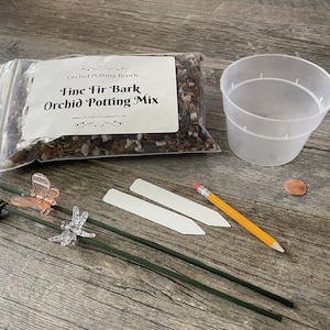 May include: A bag of fine fir bark orchid potting mix, a clear plastic pot, two white plant labels, a yellow pencil, and two green plant stakes with clear plastic butterfly and dragonfly decorations.