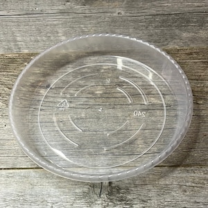 May include: A clear plastic saucer with a scalloped edge. The saucer has 240 printed on the bottom and a recycling symbol with the number 5.