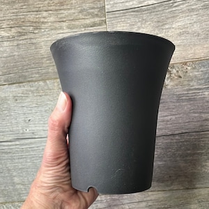May include: A black plastic plant pot with a flared top and a smooth, matte finish.