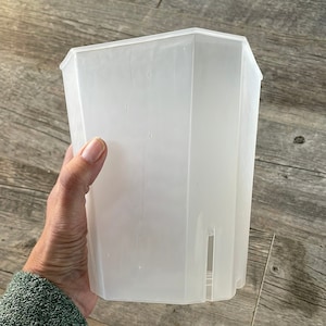 May include: A clear plastic planter with a hexagonal shape. The planter is empty and has a smooth surface.
