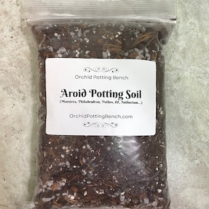 May include: A clear plastic bag filled with a brown potting mix for aroid plants. The bag has a white label that reads "Orchid Potting Bench Aroid Potting Soil (Monstera, Philodendron, Pothos, ZZ, Anthurium...) OrchidPottingBench.com".