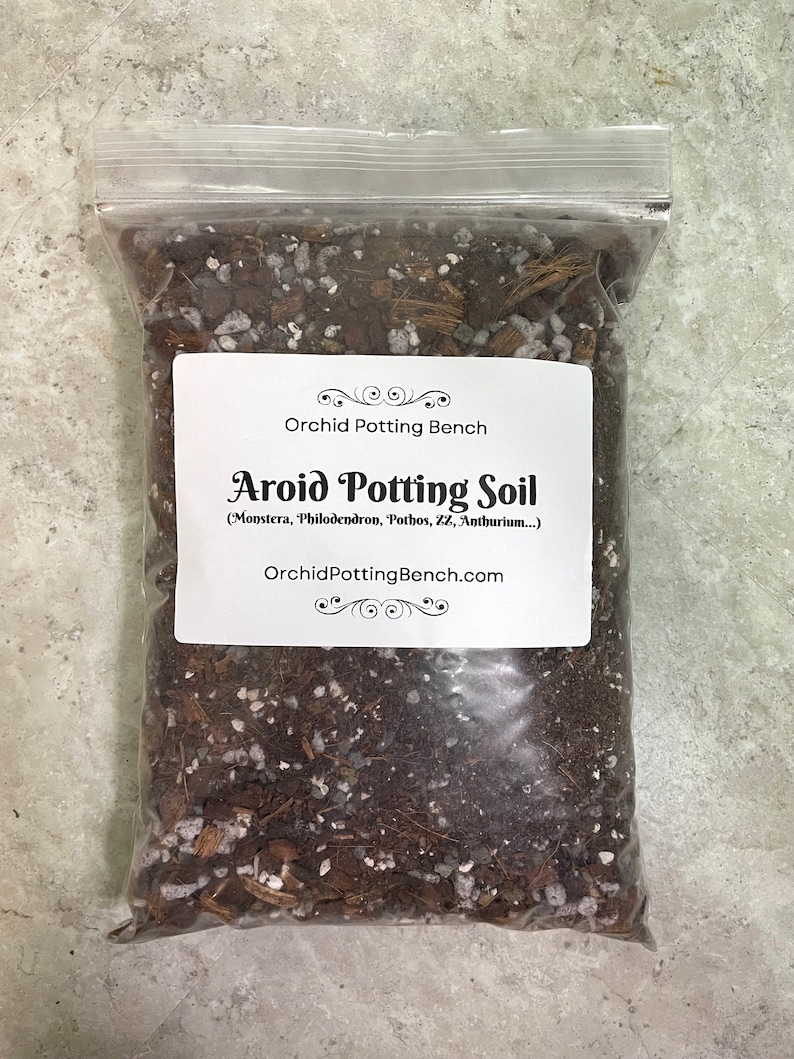 May include: A clear plastic bag filled with a brown potting mix for aroid plants. The bag has a white label that reads "Orchid Potting Bench Aroid Potting Soil (Monstera, Philodendron, Pothos, ZZ, Anthurium...) OrchidPottingBench.com".