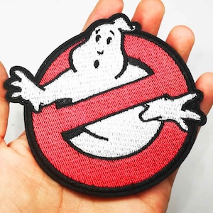 May include: Embroidered patch featuring the iconic Ghostbusters logo. The design includes a white ghost figure inside a red circle with a diagonal red line, all outlined in black. This patch is suitable for jackets, bags, or other fabric items.