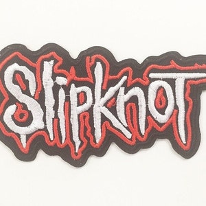 May include: Embroidered patch featuring the band name "Slipknot" in white, outlined in red, on a black background. The patch has a unique, stylized font and is likely designed for application on clothing or accessories.