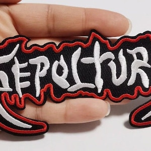 May include: Embroidered patch featuring the word "SEPULTURA" in white, stylized lettering. The patch has a black background with a red border. A decorative item for clothing or accessories.