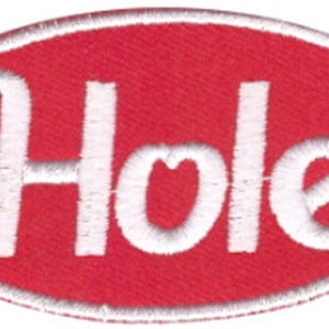 May include: A red oval patch with white embroidered text that reads "Hole". The patch has a white border and is likely designed to be sewn onto clothing or accessories. The text is in a bold, stylized font.