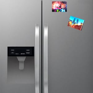 Puede incluir: Un refrigerador de acero inoxidable con dos puertas y un dispensador de hielo y agua incorporado. Dos imanes coloridos están unidos a la puerta derecha, uno con una vista de la ciudad y el otro con un espectáculo de fuegos artificiales.
