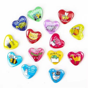 Puede incluir: Un conjunto de 14 imanes en forma de corazón con fondos coloridos e ilustraciones de animales y frases. Los imanes presentan una variedad de animales, incluyendo una tortuga, una abeja, un rinoceronte, un gato, un alce, una pantera, un armadillo, un camello, un conejo y un pato. Las frases en los imanes incluyen "For Tusk", "Take the Off", "Bee Brave", "Trumpet Cat", "Strawberry Moose", "Panther", "Arma-Pillow", "It Suddenly Me That You Exist", "Ay Up Me Duck", "Mangoat", "Catmel", "Don't Worry", and "Raugern".