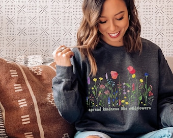 May include: A dark grey sweatshirt with a colourful floral design and the text "spread kindness like wildflowers".