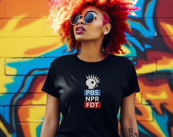 Könnte beinhalten: Schwarzes Rundhals-T-Shirt mit dem PBS NPR FDT-Logo in Weiß, Blau und Rot. Die Person trägt eine runde Sonnenbrille und hat leuchtend rote, orange und gelbe Haare. Der Hintergrund ist eine farbenfrohe Graffiti-Wand.