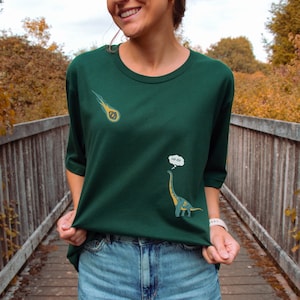 May include: A green t-shirt with a cartoon dinosaur and a comet. The dinosaur is thinking "oh oh" in a thought bubble.