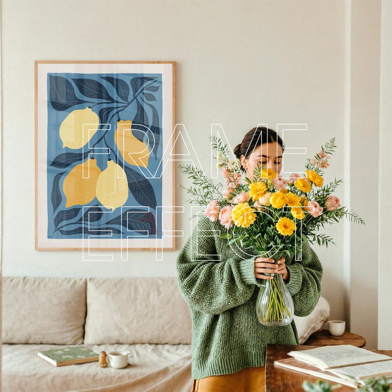 Artwork Frame Mockup Display with Woman Arranging Flowers – A modern living room bathed in warm natural light features a woman styling a floral arrangement. An empty artwork frame mockup with green-toned edges is displayed above a soft, textured sofa with a wooden table holding coffee and books, creating an elegant and artistic layout.