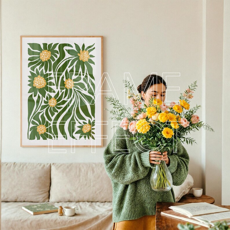 Interior Scene with Woman and Green-Toned Poster Frame Mockup – A soft, contemporary space features a woman in a muted sweater adjusting a floral bouquet. A large green-edged frame mockup hangs above a cozy sofa, ready for artwork. Natural light, coffee, and books complete the warm, gallery wall layout.