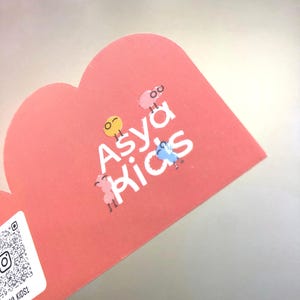May include: A pink heart-shaped sticker with the text "Asya Kids" in white. There are four small cartoon characters on the sticker, each with a different color and expression.