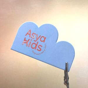 May include: A light blue cloud-shaped business card with the text "Asya Kids" in red lettering and the text "Live free like kids" in a smaller circle below.
