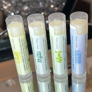 May include: Four lip balm tubes with different flavors: Lime, Mojito, Mint, and Coconut. Each tube is labeled with the flavor and ingredients, and has a white background with green and blue accents.