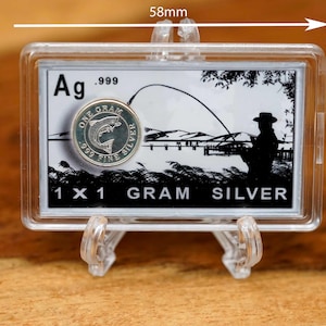 May include: A silver coin, 58mm x 38mm, in a clear plastic case. The coin is marked "ONE GRAM .999 FINE SILVER" with a fish design. The case also features a black and white illustration of a person fishing and the text "1 X 1 GRAM SILVER".