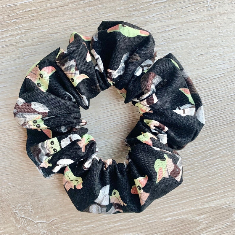 May include: Black scrunchie with a repeating pattern of green, yellow, and white cartoon characters.