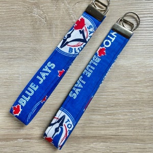 May include: Two blue and white keychains with the Toronto Blue Jays logo and the words "Blue Jays" and "Toronto".