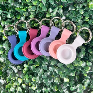 May include: Six colorful silicone keychains with silver rings. The keychains are in shades of blue, purple, pink, red, and white.