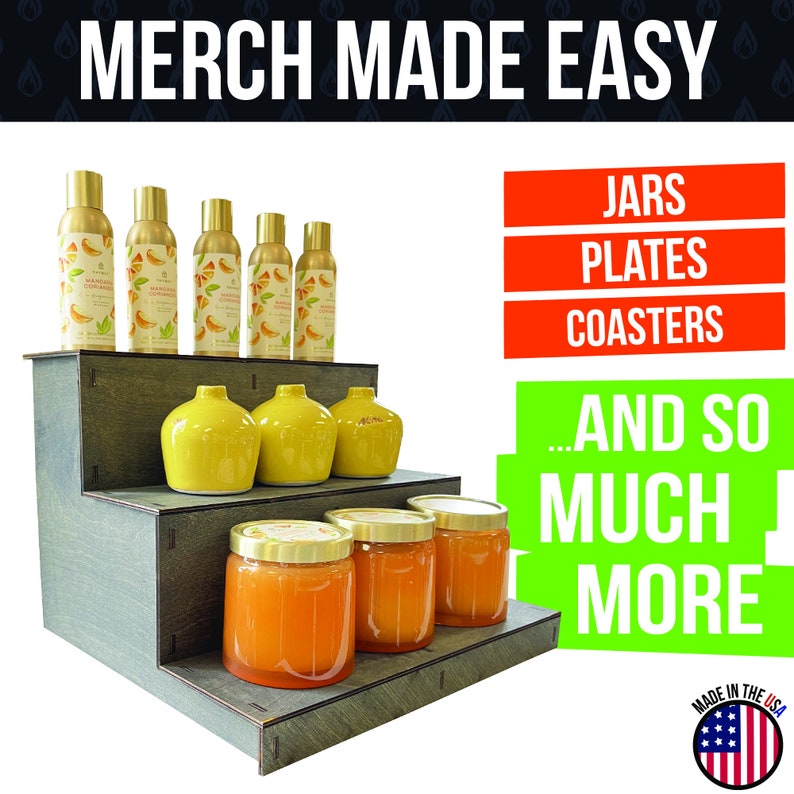 May include: A wooden display stand holds various merchandise. The top shelf features six gold spray bottles with citrus labels. The middle shelf displays yellow vases, and the bottom shelf showcases jars filled with orange contents. Text reads "MERCH MADE EASY."