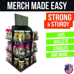 May include: A four-tiered wooden display stand with clear acrylic shelves. The stand is filled with various products, including jars, bags, and boxes. The stand is labeled "MERCH MADE EASY" and "STRONG & STURDY". The stand is also labeled with the products it can hold, including "JARS", "WALLETS", "CANDLES", and "AND MORE...".