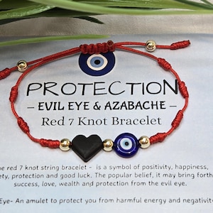 May include: Red 7 knot bracelet with a black heart, gold beads, and an evil eye charm. The bracelet is strung on red cord and features the word "PROTECTION".