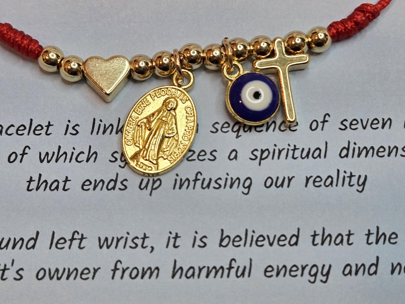 Puede incluir: Pulsera de hilo rojo con cuentas y dijes dorados. Los dijes incluyen un coraz&oacute;n, una cruz, un ojo y un medall&oacute;n con la imagen de una persona. La pulsera est&aacute; vinculada a una secuencia de siete.