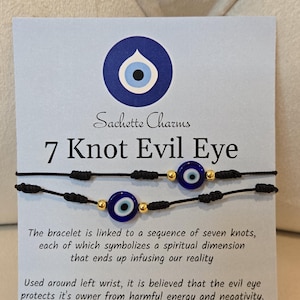 May include: Two black cord bracelets with blue and white evil eye charms and gold beads. The card reads "Sachette Charms 7 Knot Evil Eye". The text on the card describes the bracelet's spiritual symbolism and protective properties.