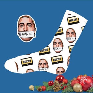 May include: White socks featuring a repeating pattern of a cartoon face with the text "My name is..." on a strip of paper over the mouth, and cassette tapes. The background is blue.