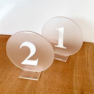 Hochzeitstischmarkierungen aus satiniertem Plexiglas und glänzend weißen Zahlen.